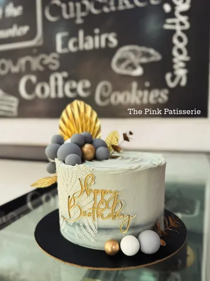 A sophisticated grey and white cake with a knitted texture, gold accents, and a "Happy Birthday" topper.