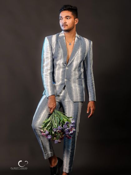 A full-length shot that balances fashion with a touch of romance. The flowers provide a beautiful color accent against the cool tones of the suit.