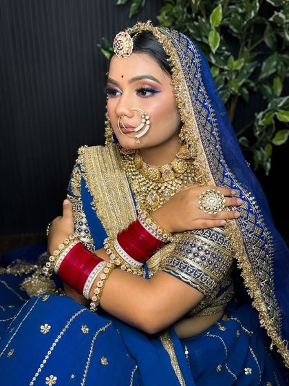 A classic pose of the Rajputi bride in her blue lehenga. The makeup is bold and regal, perfectly matching the grandeur of her outfit.