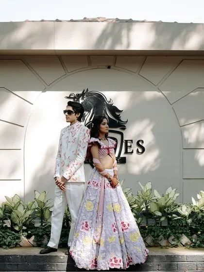 A stylish, full-length portrait of the couple at their carnival-themed event. Their confident poses and unique outfits showcase their modern and fashionable style.