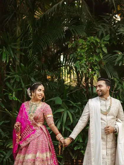 A classic portrait of the couple holding hands, their vibrant outfits popping against the natural greenery.