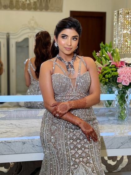 Reception vibes are all about glam. This look features a silver-toned gown with complementary cool-toned makeup and a voluminous ponytail, a style you'll learn to create.