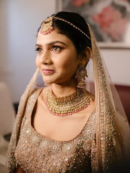 A beautiful profile shot of the bride. The makeup is soft and romantic, with a focus on enhancing her natural features.