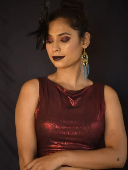 A close-up showing the dark, vampy lip and feathered accessory, key elements of this high-fashion concept.