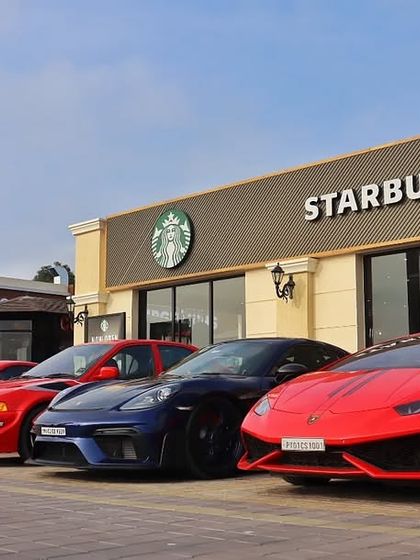 An impressive lineup of supercars, including a Lamborghini and several Porsches, ready for an early coffee run at our Starbucks outlet.