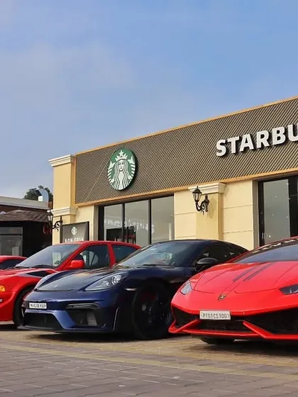 An impressive lineup of supercars, including a Lamborghini and several Porsches, ready for an early coffee run at our Starbucks outlet.