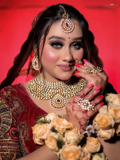 This portrait focuses on the heavy kundan necklace and matching jewelry, complementing the rich red bridal attire.