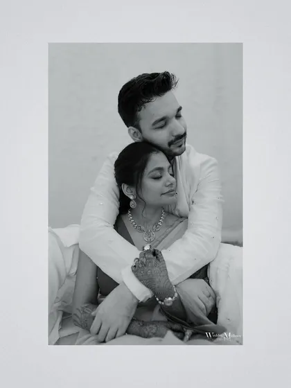 A tender black and white portrait of the groom embracing the bride from behind. This intimate shot focuses on their connection and the quiet moments of love.