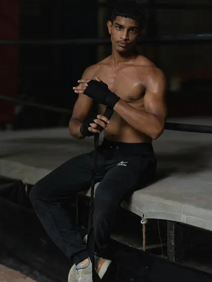 The calm before the storm. A young boxer wraps his hands, a ritual that signifies focus and preparation for the battle ahead.