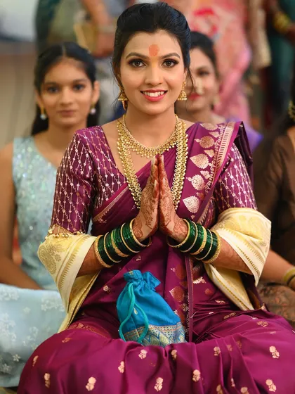 A beautiful moment from an engagement ceremony. The bride's purple saree and gold jewellery are perfectly complemented by her radiant makeup.