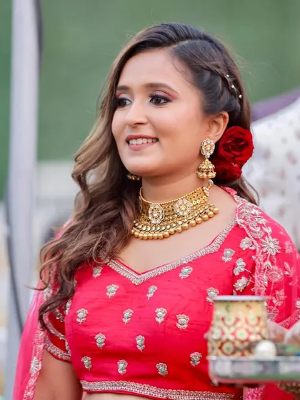 The bride's sister looking radiant in red. The makeup is classic and festive, with a bold lip and a beautiful rose in her hair.