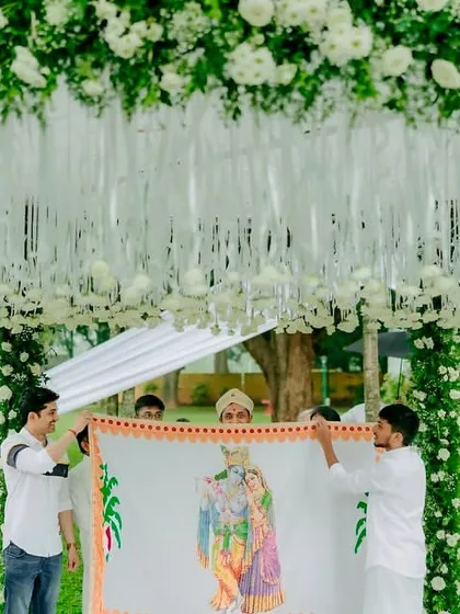 A sacred moment before the vows. The Antarpat ceremony, framed by a minimal mandap of white florals and fresh greenery, creates a sense of serene anticipation.