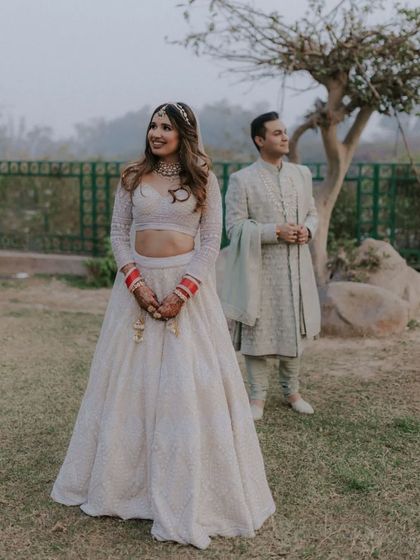 A beautiful portrait of the couple in an outdoor setting, with the bride in the foreground and the groom slightly behind, creating a sense of depth.