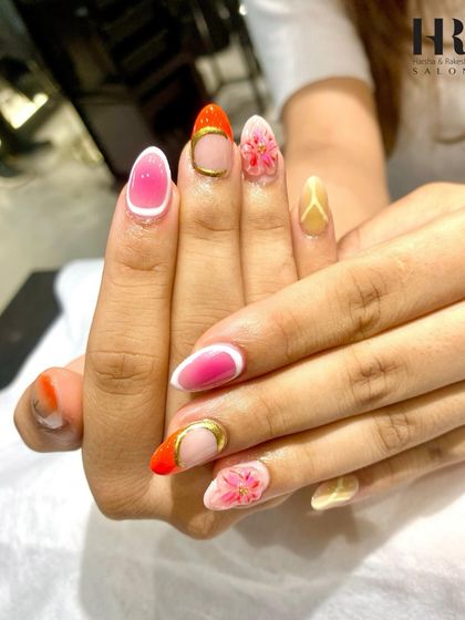 A vibrant and artistic mix of colours and textures. This nail set includes pink and orange tones, floral details, and gold accents, creating a playful and eye-catching design.