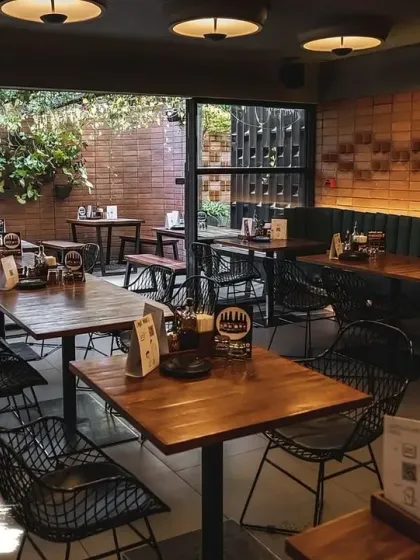 The cozy interior of our Indiranagar outlet, with its mix of indoor and outdoor seating and lush green wall.