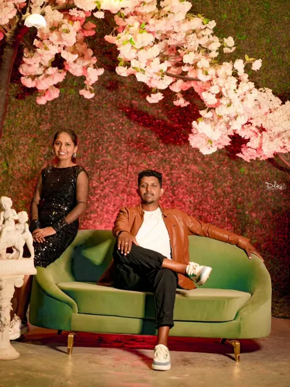 A relaxed and stylish pose on a modern green sofa. The cherry blossom backdrop adds a touch of romance and softness to this indoor shot.