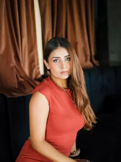A beautiful close-up portrait. The warm tones of the background complement the model's outfit, and the soft lighting is incredibly flattering.