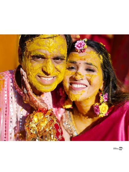 A joyful selfie-style close-up of the couple, their faces covered in turmeric. This photo is a perfect testament to the fun and messy nature of the Haldi ceremony.