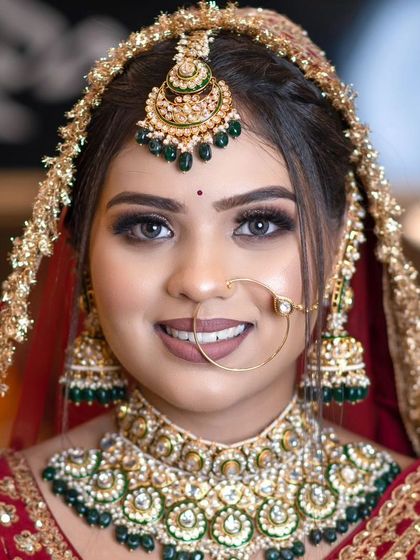 A smiling bride wearing a classic green and gold Kundan choker with a matching nath and maang tikka. This is a timeless choice for any bride.