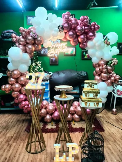 A chic decoration for a 27th birthday party. This setup uses a beautiful combination of rose gold and white balloons, with golden pedestals and a light-up '27' to mark the age.