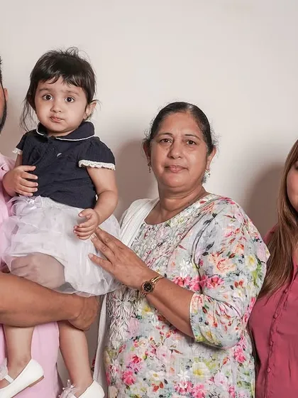 A classic family portrait with three generations, taken against a clean white backdrop during an in-home studio session.