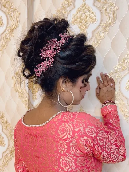 The back view of a party hairstyle, showing a voluminous, messy updo accessorized with a beautiful pink crystal hairpiece.