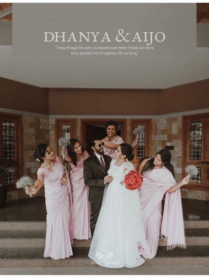 The couple posing with their bridesmaids, who are dressed in lovely pink sarees, creating a beautiful color palette.