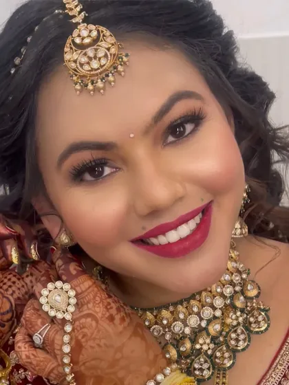 A close-up of a bride's radiant smile. Her makeup features a classic red lip and shimmery gold eyes, a timeless combination for any North Indian bride.