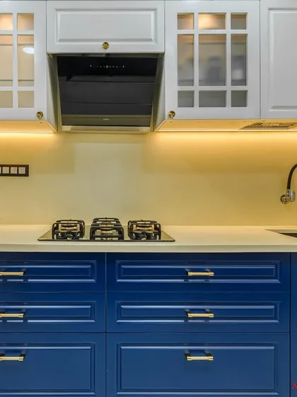 A close-up of the cooking area in the blue and white PU kitchen, with glass-fronted upper cabinets.