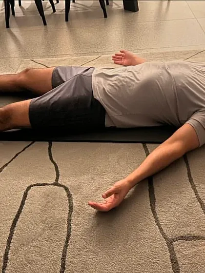 A moment of deep rest in Savasana, illuminated by a candle. This pose is crucial for integrating the benefits of a yoga practice, allowing the body and mind to absorb the energy created.