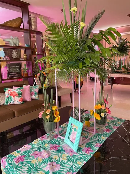 The flamingo theme was carried through to the table decor, with tropical print runners and centerpieces featuring lush palm leaves and floral arrangements.