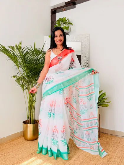 A beautiful floral print on a white cotton linen base with a saffron and green border. This is a very soft and feminine take on a tricolor saree.