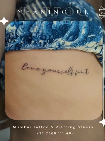 "love yourself first." A crucial reminder inked in a delicate, fine line script on the ribs. This is a popular placement for personal and private messages.