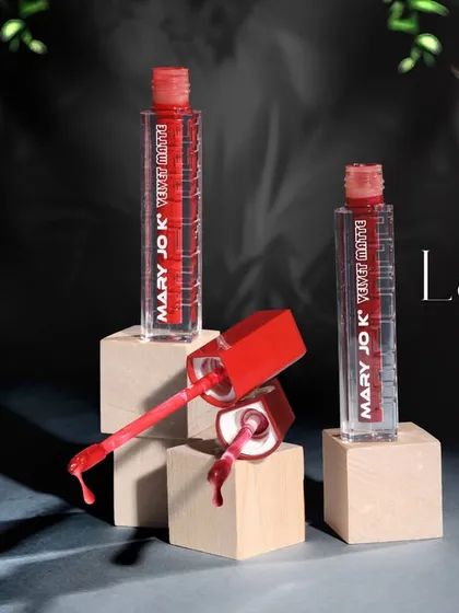 A creative product shot of nail lacquer bottles arranged on wooden blocks. The composition and dark background highlight the product's vibrant color and unique packaging.