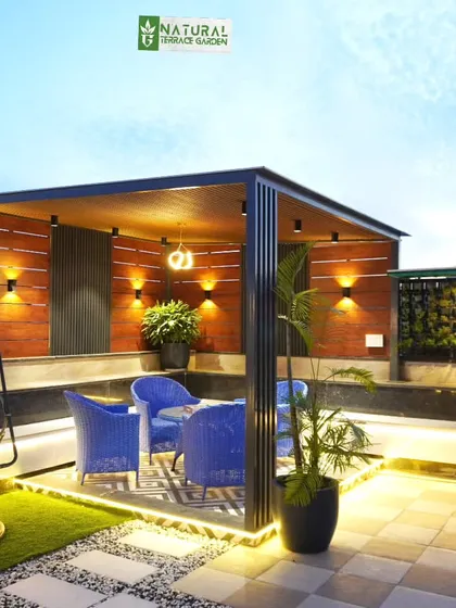 A stylish pergola in Palam Vihar with bright blue chairs, a swing, and a backdrop of vertical gardens and wood paneling.