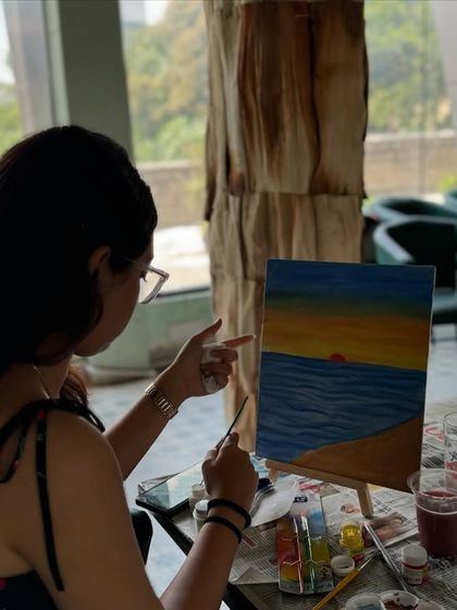 A participant painting a beautiful sunset over the ocean. Canvas painting is a classic way to relax and create.