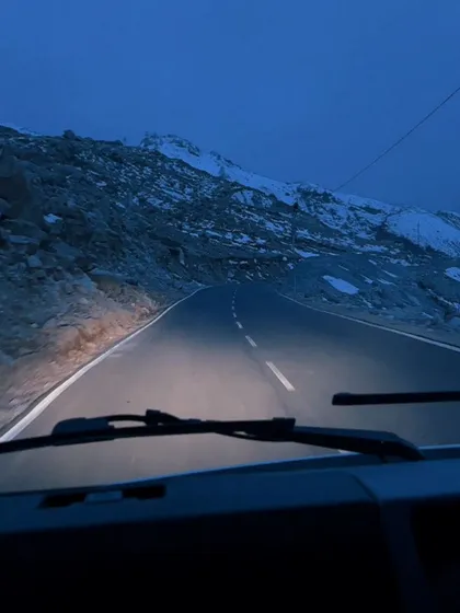 A point-of-view shot from a car driving on a mountain road at dusk, creating a sense of journey.