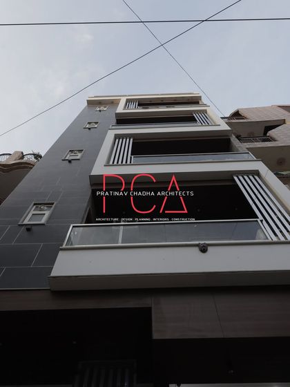 An upward-looking daytime shot of 'The Cursive Abode', emphasizing the clean architectural lines against the sky and the modern aesthetic of the design.