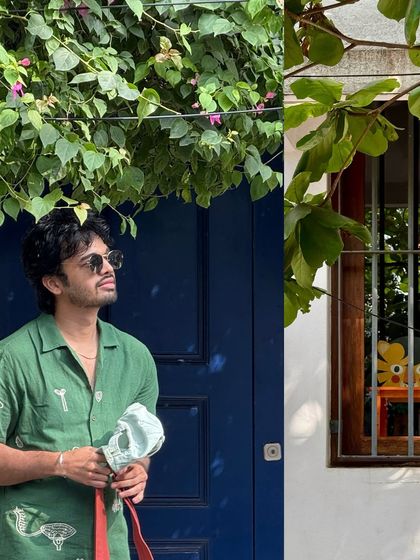 A self-portrait under the shade of a leafy tree, in front of a bright blue door in Pondicherry.