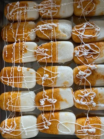 A tray of savory mini idlis with a spicy topping and a creamy drizzle, perfect as a bite-sized starter for any Indian event.
