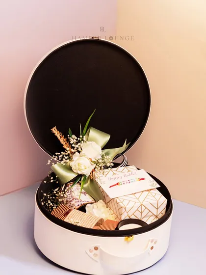 The luxe white leatherette box, shown open to reveal the curated gifts inside. It’s not just a hamper, it’s a keepsake box they can use long after Rakhi.