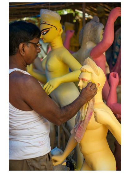 An artisan in Kumartuli, the potters' quarter, gives the final touches to an idol. This is where the divine forms are painstakingly crafted by hand.