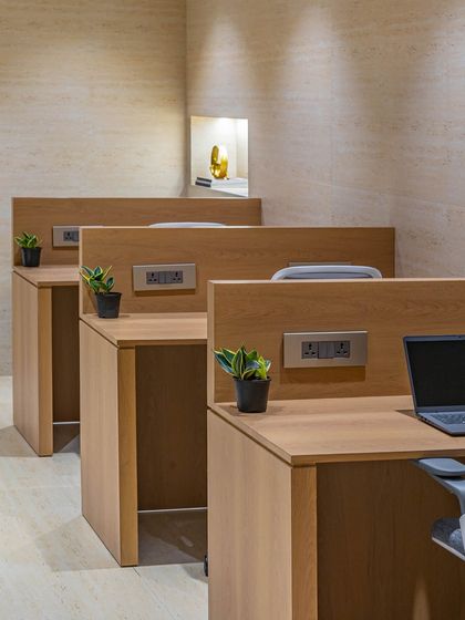 A close-up of the custom workstations, showing the clean lines, integrated power outlets, and the consistent wood laminate finish that ties the entire space together.