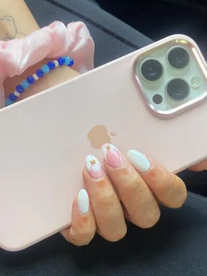 A delicate and pretty set with milky white nails and a pink watercolor-style floral accent nail.