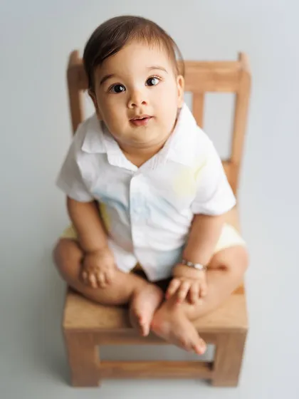 A simple and classic portrait for a baby boy's milestone session. Seated on a small wooden chair, his curious expression is the star of the show.