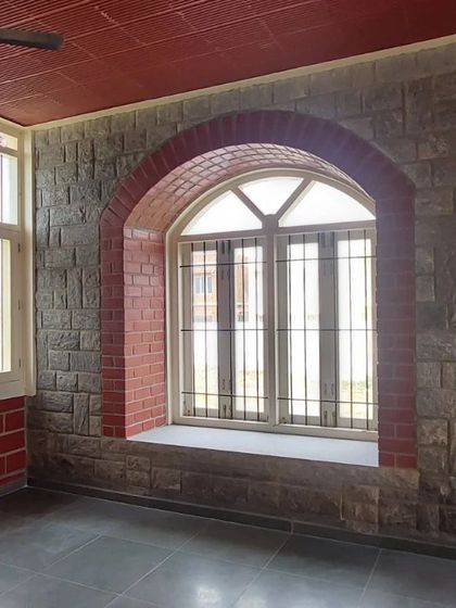 A beautiful arched window set within a stone wall, with a brick arch providing a contrasting frame.