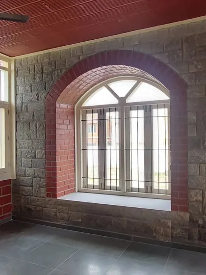 A beautiful arched window set within a stone wall, with a brick arch providing a contrasting frame.