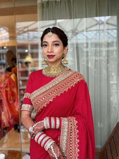 This portrait showcases a classic red saree look for a South Indian wedding. The makeup is kept elegant and timeless to honor the tradition.