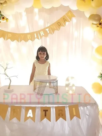 A simple and sweet yellow and white themed party with a birthday girl posing by the cake table.