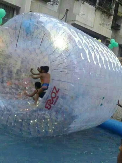 Kids enjoying the water zorbing roller inside an inflatable pool. They can walk, run, and tumble on the water's surface in this giant inflatable ball.